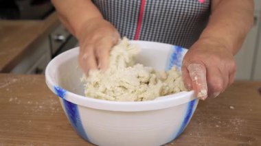 Elleri kasede hamur yoğurmak. Tanınmayan kişi bileşenleri kütleye karıştırıyor. Çalışma karışımı yumuşak formda. Ev yapımı ekmek için hamur hazırlıyorum.