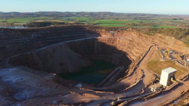 Teraslı kazı ve derin çukur dolduran su ile açık maden ocağı. Büyük ölçekli taş ocağı madenciliği ve su basmış zemini çevreleyen kaya duvarları. Endüstriyel kazı alanına sahip açık çukur madenciliğinin hava görüntüsü