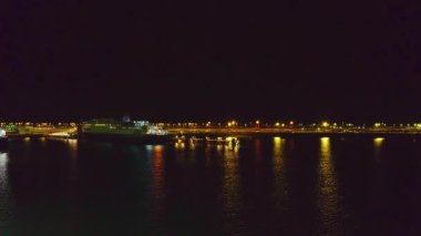 Gece Port Calais 'e yaklaşan feribot, liman ışıklarını suya yansıtıyor. Fransa 'yı birbirine bağlayan denizcilik rotaları araçları kanaldan geçirirken. Aydınlatılmış rıhtımlarla gece deniz manzarası yolculuk atmosferi yaratıyor.