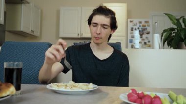 Adam mutfakta oturmuş düşünceli bir ifadeyle hamur tatlısı yiyor. Adam evde yemek yiyor. Dalgın suratlı hamur tatlısı yiyor. Mutfakta yansıtıcı bakışlarla yemek yiyen bir erkek.
