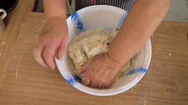 Kasede elleri olan hamur sıkıştırmak. Tanınmayan kişi konteynırdaki karışımı yoğuruyor. Kitle elastik formda çalışıyor. Ev yapımı ekmek için hamur hazırlıyorum.