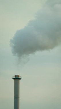Sanayi bacası bulutlu gökyüzüne yoğun duman yayıyor. Fabrika hava kirliliği ve çevreyi etkileyen zararlı emisyonlar, dikey yönelim. İklim değişikliği etkisi ve endüstriyel emisyon kavramı