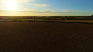 Bereketli toprağın üzerine akşam güneşiyle sürülmüş tarım tarlaları. Sıcak gökyüzünün altında karanlık ekili arazisi olan geniş bir kırsal alan. Dokulu toprak ve yumuşak ufukta parlayan açık tarım arazisi
