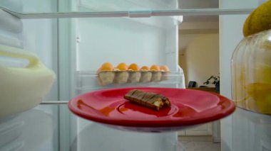 Çocuk cep telefonuyla konuşurken buzdolabını açıyor, ısırılmış çikolatayı fark ediyor, telefonu şoka sokuyor, buzdolabının içini görüyor. Genç, şaşkın ve telaşlı bir erkek. Adam beklenmedik bir keşfe inanmayarak tepki veriyor.