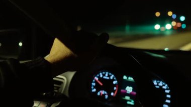 Tanımlanamayan bir adam gece yolunda ışıklara doğru sürerken direksiyona el basmak. Erkek seyir otoyolu, yaklaşan farlar gibi sürükleyici tekerlek parlıyor. Karanlık caddede araba sürüyorum, önümüzde aydınlık bir yol var.