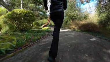 Saldırgandan kaçarken parkta kadın bacakları üzerinde koşmak. Bahçe yolunda koşan tanınmayan bir kadının düşük açılı görüntüsü suç gerilimi yaratıyor. Yeşil park manzarasında hızlı hareket tehlike, takip, hayatta kalma