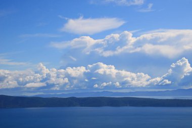 Mavi gökyüzü, denizin üstünde beyaz bulutlar