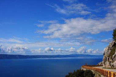 Mavi gökyüzü, denizin üstünde beyaz bulutlar