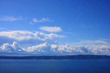Mavi gökyüzü, denizin üstünde beyaz bulutlar