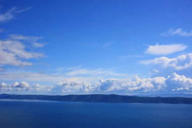 Mavi gökyüzü, denizin üstünde beyaz bulutlar