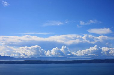 Mavi gökyüzü, denizin üstünde beyaz bulutlar