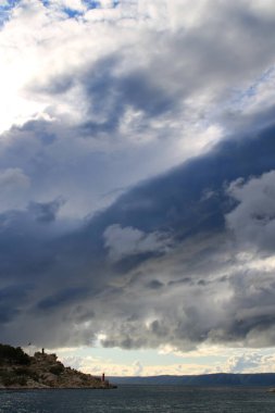 Mavi gökyüzü, denizin üstünde beyaz bulutlar