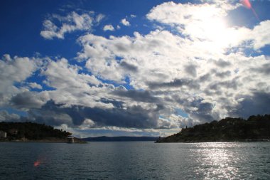 Mavi gökyüzü, denizin üstünde beyaz bulutlar