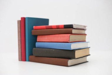Masanın üzerinde beyaz arkaplanı olan kitaplar
