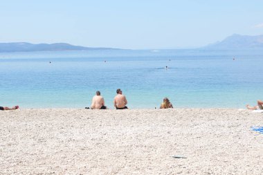 Makarska, Hırvatistan, 04.06.2021 İlk yüzücüler, Coronavirus salgınından sonra bu sezon ilk turistlerin geldiği Makarska 'daki plajların keyfini çıkarıyorlar.