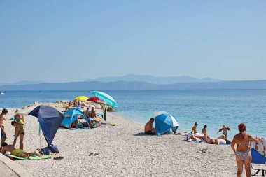 Podgora, Hırvatistan, 14.08.2021. Turistler, Polonya, Almanya, Macaristan, Çek Cumhuriyeti, Slovakya, Avusturya, Slovenya, Sırbistan ve Bosna-Hersek 'ten gelen turistlerin en sevdiği tatil beldesi olan Makarska Riviera, Podgora' daki plajın keyfini çıkarıyorlar.