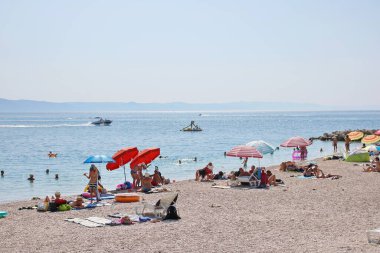 Podgora, Hırvatistan, 14.08.2021. Turistler, Polonya, Almanya, Macaristan, Çek Cumhuriyeti, Slovakya, Avusturya, Slovenya, Sırbistan ve Bosna-Hersek 'ten gelen turistlerin en sevdiği tatil beldesi olan Makarska Riviera, Podgora' daki plajın keyfini çıkarıyorlar.