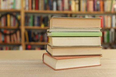 Kütüphanedeki ahşap masada yığınla kitap.