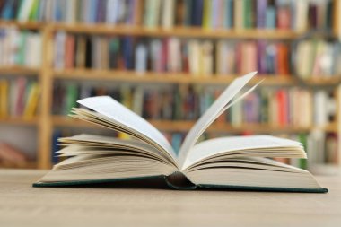 Bulanık arka plana karşı ahşap masadaki kitap yığını