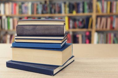 Tahta bir masanın önünde kitap yığını