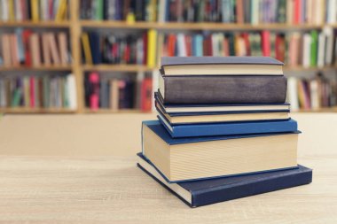 Kütüphanedeki ahşap masada yığınla kitap.