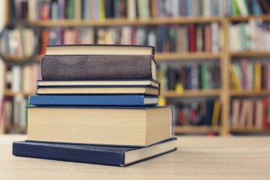 Ahşap duvarın önünde bir yığın kitap.