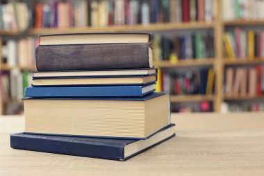 Kütüphanedeki ahşap masada yığınla kitap.