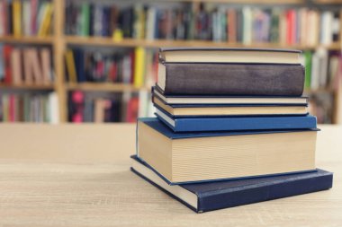 Kütüphanedeki ahşap masada yığınla kitap.