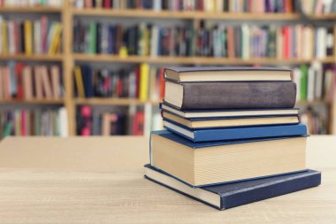 Kütüphanedeki ahşap masada yığınla kitap.