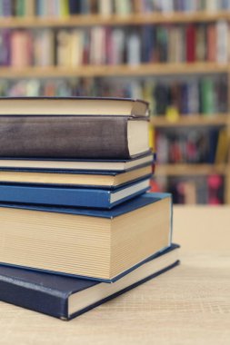 Ahşap masanın üzerinde bulanık arka plana karşı bir yığın kitap. Metin için boşluk