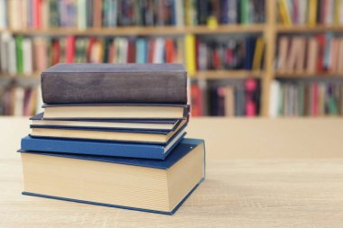 Kütüphanedeki ahşap masada yığınla kitap. Metin için boşluk