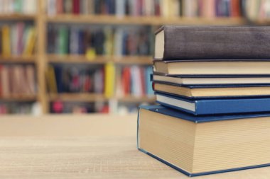 Kütüphanedeki ahşap masada yığınla kitap.