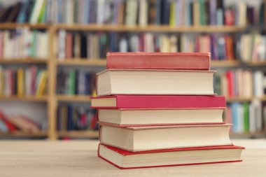 Tahta masanın üzerinde bir yığın kitap var.