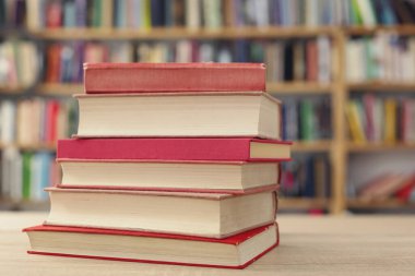 Kütüphanedeki ahşap masada yığınla kitap.