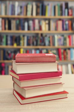 Ahşap masada bir yığın kitap ve kırmızı kütüphane. Okula geri dön.