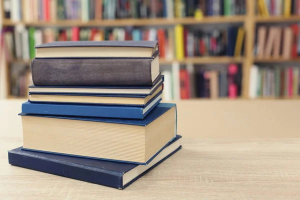 Kütüphanedeki ahşap masada yığınla kitap.