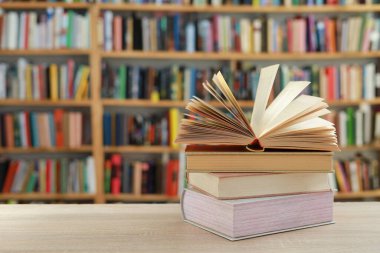 Kütüphanedeki ahşap masada yığınla kitap.