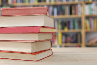 Kütüphanedeki ahşap masada yığınla kitap.