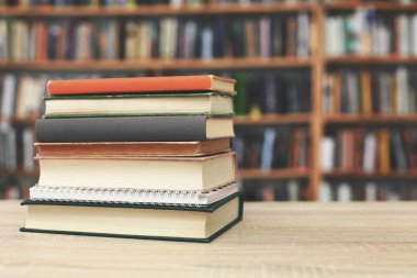 Kütüphanedeki ahşap masada yığınla kitap.