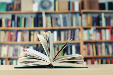 Kütüphanedeki ahşap masanın üzerinde açık bir kitap