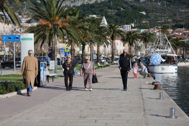 Makarska, Hırvatistan, 01.02.2026.İnsanlar kışın başında liman boyunca yürüyorlar.