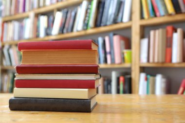 Kütüphanedeki ahşap masada yığınla kitap.