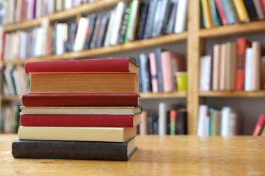 Kütüphanedeki ahşap rafta yığınla kitap.