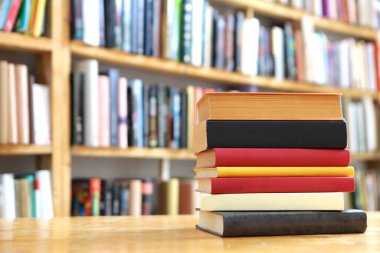 Kütüphanedeki ahşap masada yığınla kitap.