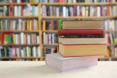 Kütüphanedeki ahşap masa üzerinde kitap yığını, eğitim geçmişi