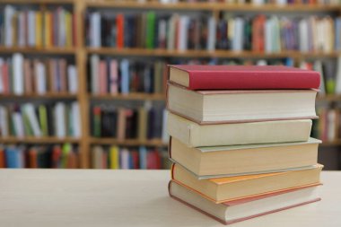 Kütüphanedeki ahşap masada yığınla kitap.