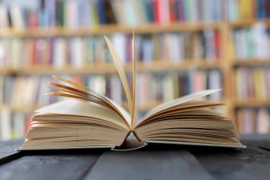 Tahta bir arka planda kitap yığınıyla birlikte açık bir kitap