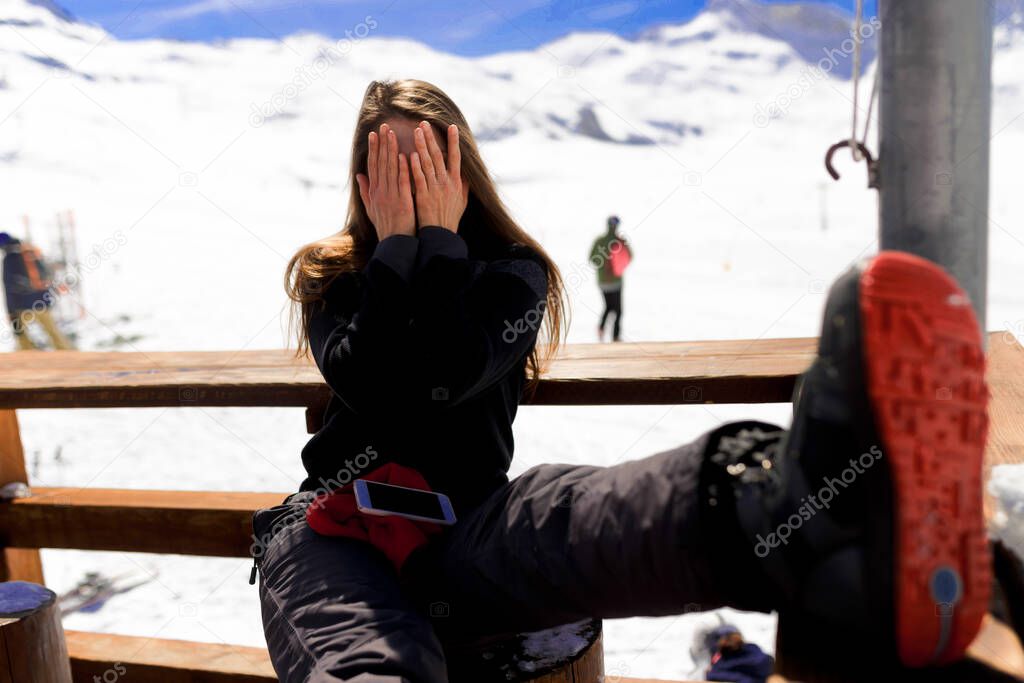 Young woman covered his face with her hands with mountain view during ski vacation in Alps backgrounds.