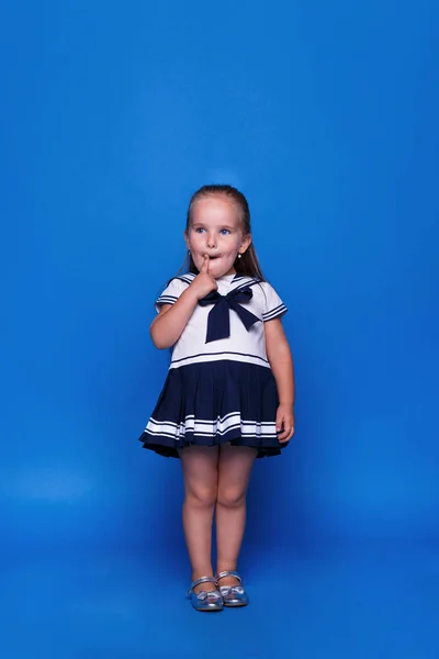 Close-up portret van een klein geweldig meisje met blauwe ogen en een open mond op een blauwe achtergrond. Ruimte voor tekst. — Stockfoto