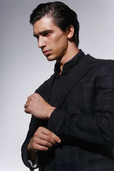 Close Up portrait of a handsome serious young man in black suit over white dark background. Vertical view. — Stock Photo, Image